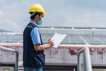 Worker with clipboard at factory building background