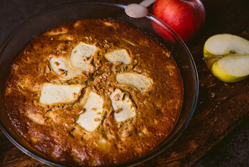 close up of a fresh homemade apple pie on rustic brown burlap fabric with soft natural light, with apples and cinnamon sticks, freshly oven and appetizing, with dry fruits on top and apple slices