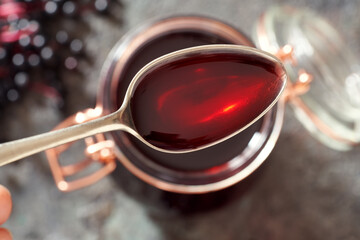 Black elderberry syrup on a spoon, top view