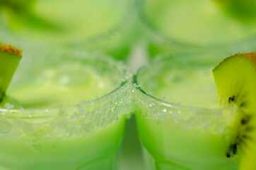 Fruit shot drink based on alcohol, liqueur and cream, decorated with green sugar crystals and a slice of fresh kiwi