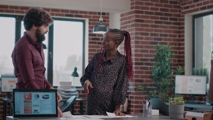 Multi ethnic team of people giving highfive while working on business project. Woman expecting baby and doing teamwork with colleague to design charts on documents. Pregant employee