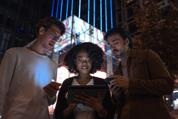 People reading and looking at the tablet while standing at the street with night lights