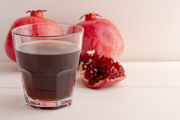 A glass of fresh pomegranate juice and pomegranates in the background. Copy space. Selective focus.