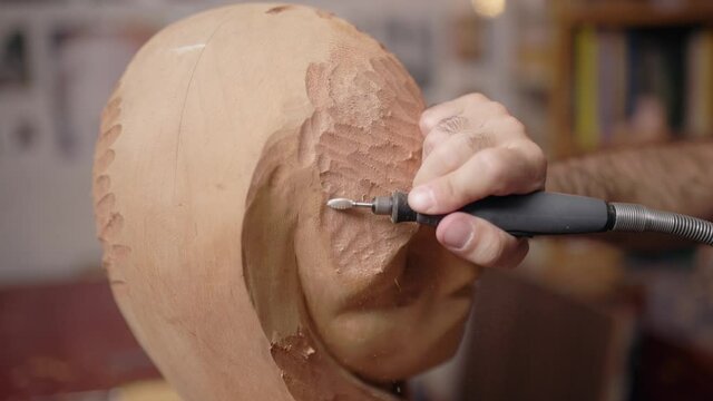 Anonymous craftsman carving wooden sculpture in workshop