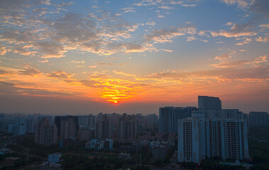 Fototapeta premium Colorful sunset,sky, mackerel clouds in Delhi NCR city Gurugram,Haryana,India.View of city's residential apartments,commercial hub during monsoon on July 24,2021.