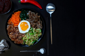 Pibimbap is a popular dish of traditional Korean cuisine made from rice, seafood, zucchini, mushrooms, carrots, spinach, eggs. top view. copy space
