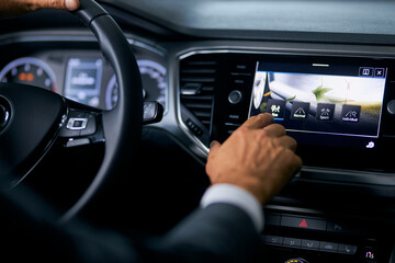 Caucasian male buyer testing electronic multimedia of modern car at showroom. Close up of male...