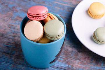 Stacked macarons of different flavors in a blue mug.