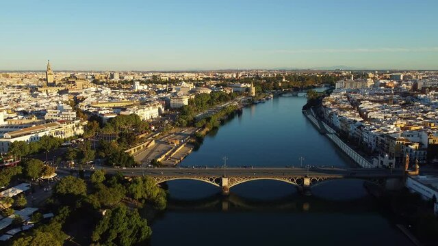 Aerial drone footage of the Seville city along the Guadalquivir canal with various landmark such as the cathedral, the Torre del Oro and the Bull area in Andalusia, Spain