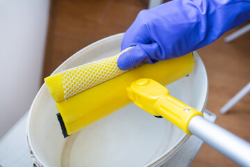 House cleaning and cleaning concept. A young girl in purple gloves squeezes water out of a mop.