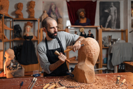Focused craftsman shaping wooden detail with chisel
