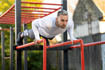 Handsome man street pushup workout on parallel bars, outdoors workout