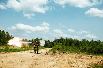 a soldier shoots an RPG. training shooting from a rocket launcher at a military training ground. a rocket projectile flies out of a gun in the hands of a soldier