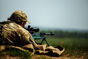 a sniper shoots lying down with a rifle with an optical sight - obrazy, fototapety, plakaty