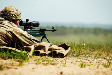 a sniper shoots lying down with a rifle with an optical sight