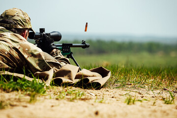 Fototapeta na wymiar a sniper shoots lying down with a rifle with an optical sight. the spent cartridge case flies out of the weapon