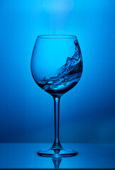 Splash drink in glass of wine on blue background