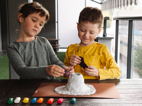 Concentrated kids molding plasticine while creating volcano figurine
