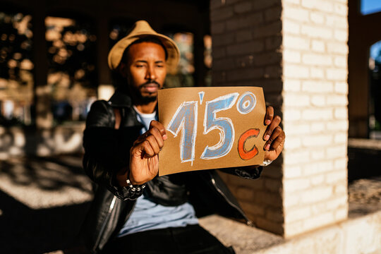 Black man showing paper with weather temperature