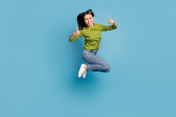 Photo of charming promoter lady raise two thumbs up wear green shirt jeans sneakers isolated blue...