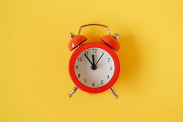 Red alarm clock on yellow background.