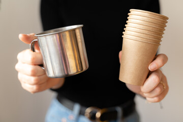 Woman in black shirt holding paper cup and metal reusable mug. Sustainable choice