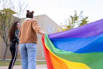 Unrecognizable homosexual couple with rainbow flag