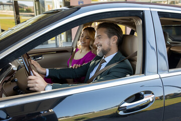 Luxury business couple driving in a car