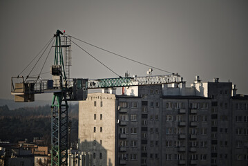 Duży dźwig budowlany (żuraw )   na tle bloku mieszkalnego . Budowa . A large construction crane  against the background of an apartment block. Building .