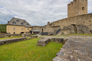Fototapeta na wymiar Medieval castle of Bourscheid, predominantly open air ruin with dilapidated stone walls, a tower, courtyards and green grass, cloudy day with a sky covered in gray clouds, Luxembourg