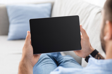 Cropped mature guy on couch, relax and look at tablet with empty screen, watch blog, video and...