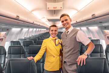 Cheerful airline workers standing in aircraft passenger salon
