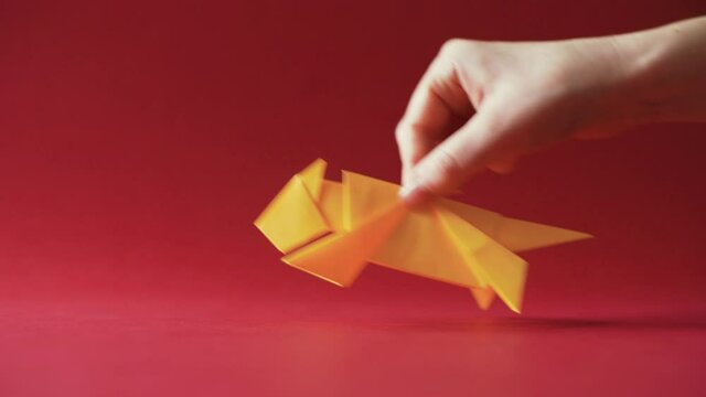 Hand moving yellow Origami Tiger on red background. Symbol for Chinese new year. Tiger is the Chinese zodiac sign for 2022. Golden animal made with traditional Japanese paper folding technique. 4K.