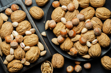 Walnuts in a plate on a dark concrete background. Nuts are a source of vegetable protein and vitamins. For a healthy and vegetarian diet. Flat top view
