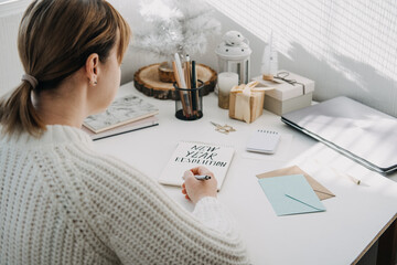 2022 goals, New year resolution. Woman in white sweater writing Text New year resolution in open...