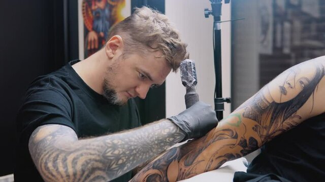 Professional tattoo in compliance with sanitary health safety standards. The process of tattooing a man's hand in a tattoo parlor