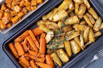 Baked parsnip, carrot and sweet potato. Roasted root vegetable top view closeup. - obrazy, fototapety, plakaty