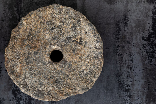 Old quern-stone. Ancient round stone with hole for hand grinding.