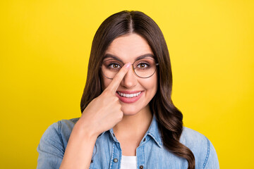 Photo of friendly pretty young woman dressed denim shirt finger glasses smiling isolated yellow...