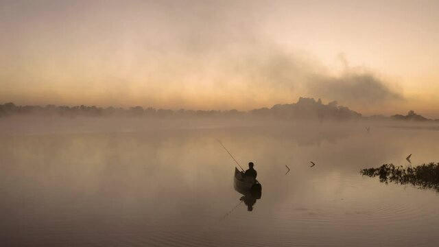 Aerial of a man that is fishing by himself in a lake before sunrise, Imire, Zimbabwe