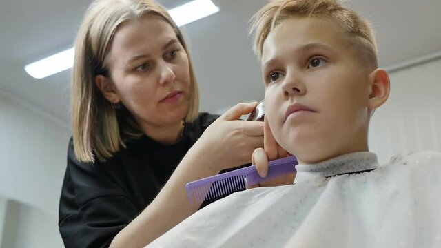 a teenage girl has a haircut by a hairdresser. Short fashionable hairstyle with puffs on the sides and back of the head. Look up. Slow motion