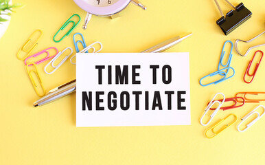 Top view of a business card with text TIME TO NEGOTIATE, on a yellow background.