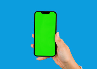 Female hand holding a smartphone with Chroma Key on the screen. Blue background and Green screen.