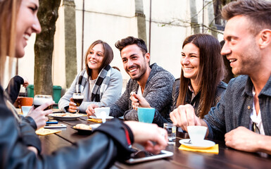 People tasting hot drinks at coffee restaurant dehor - Milenial friends talking and having fun together at sidewalk cafe - Life style concept with happy men and women at bar cafeteria on bright filter