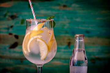 Glass of gin and tonic with ice and lemon, decorated with colored candies, sugar and a straw, a...