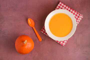 Plate with pumpkin soup on a light background