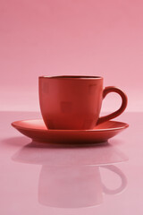 red mug on a pink background with reflection