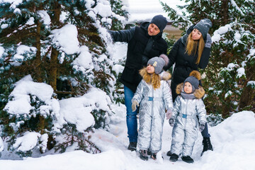 Fototapeta na wymiar Handsome family mom and dad and his little cute daughter with son are having fun outdoors in winter in winter clothes. They enjoy spending time together. Family concept.