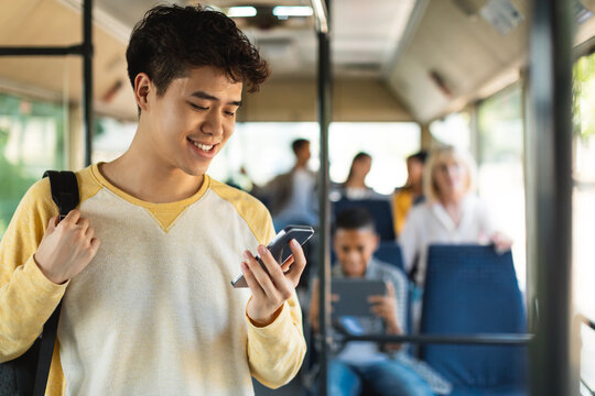 Haapy Asian guy using cell phone in bus