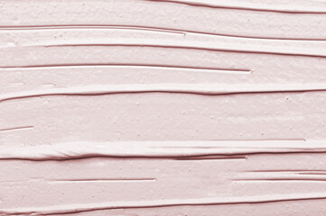 Texture of light pink cleansing facial mask made of clay for skincare with brush traces as...